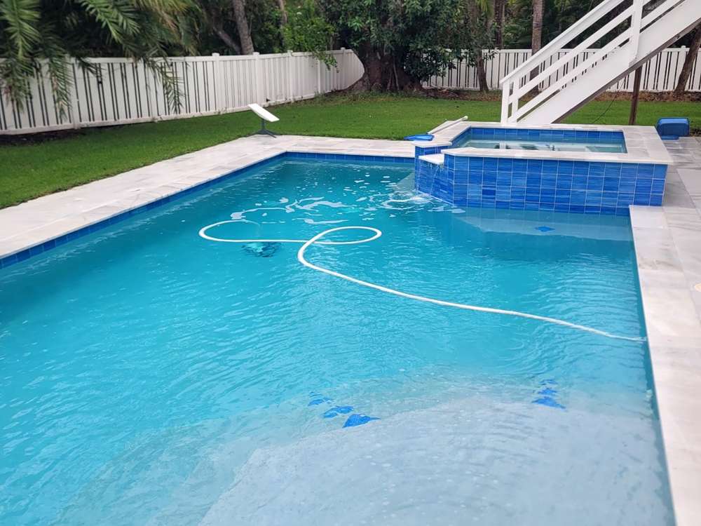 Pool and spa with a paver deck and turf lawn